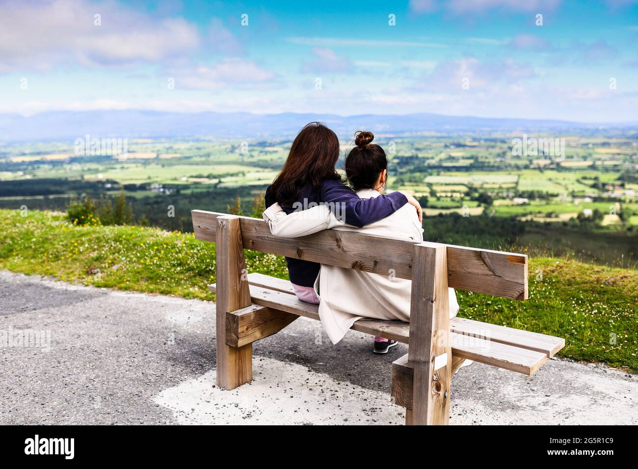Two friends sitting in a bench near the edge of the road at Vee Pass in the Knockmealdown mountains in Clogheen county Tipperary, Ireland Stock Photo