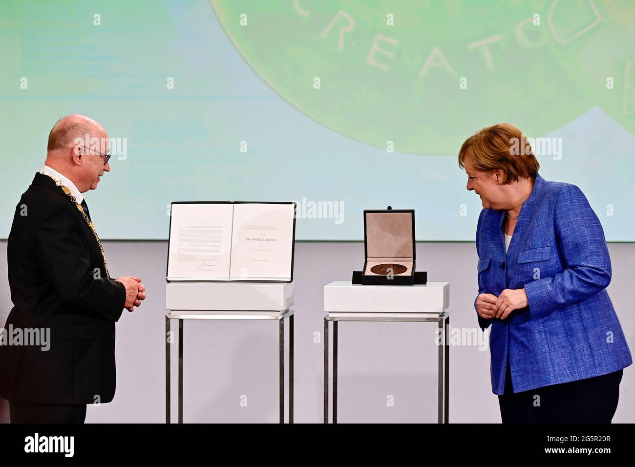German Chancellor Angela Merkel looks at the Harnack Medal that she has been awarded, next to Max Planck Society President Martin Stratmann, at Humboldt Carre in Berlin, Germany June 29, 2021. Tobias Schwarz/Pool via REUTERS Stock Photo