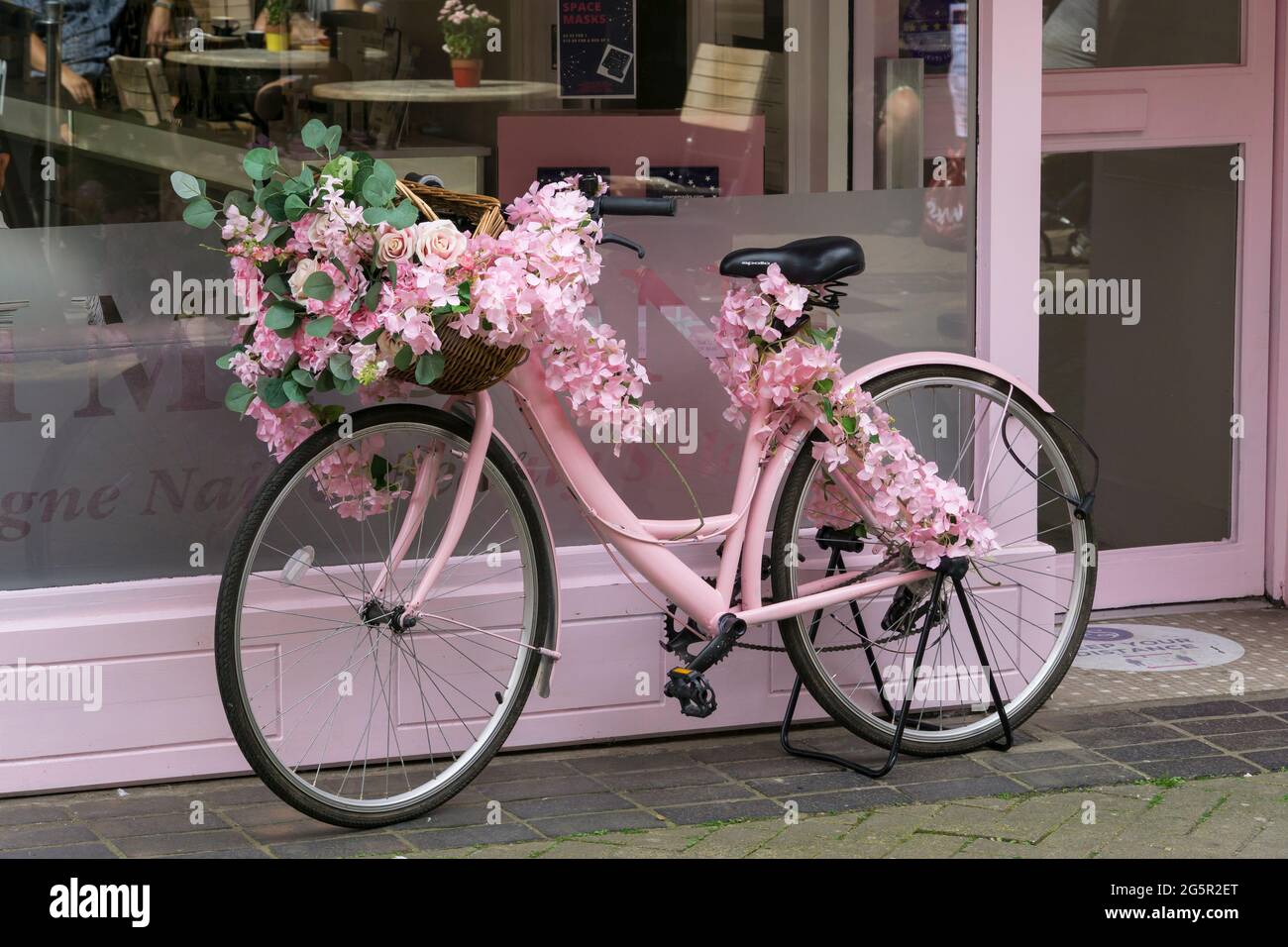 Pink floral decoration on pink bicycle outside of Simpsons Champagne Nail & Beauty Salon Guildhall  Street Lincoln City 2021 Stock Photo