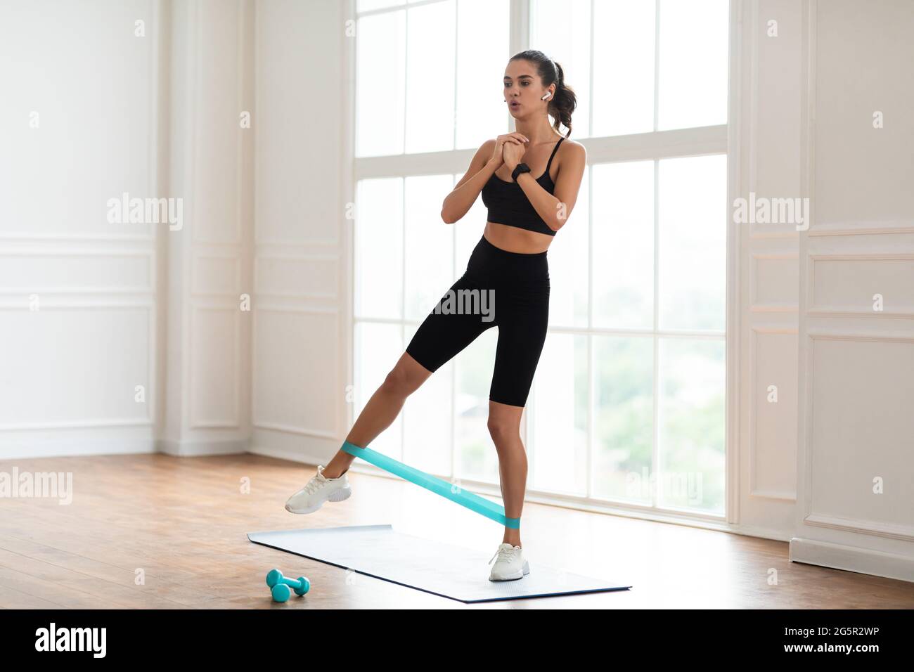 Focused Woman In Sportswear Exercising With Band Stock Photo