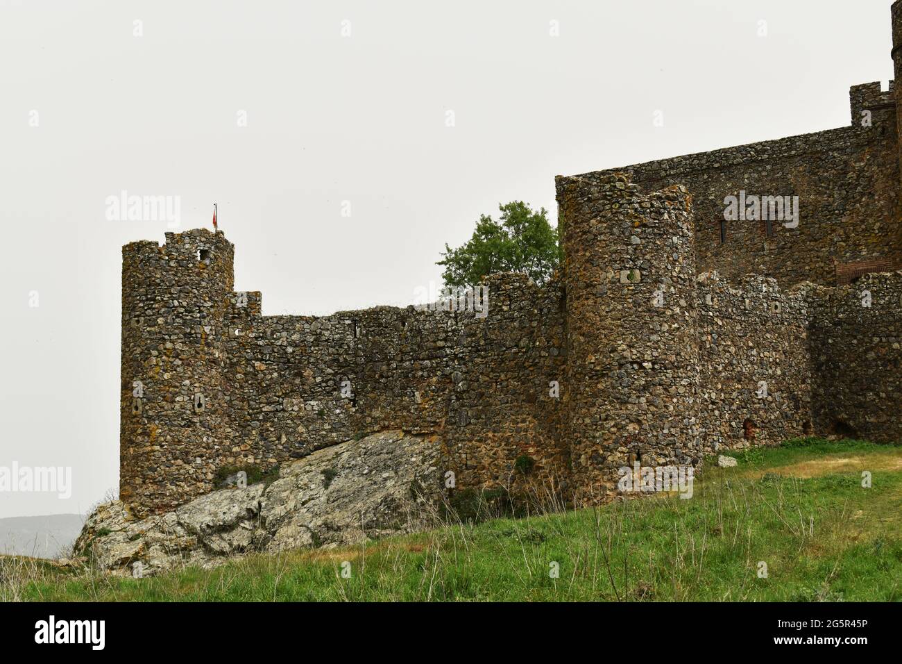 Old castle in the top of a hill in Salvatierra de los Barros with trees and grass Stock Photo