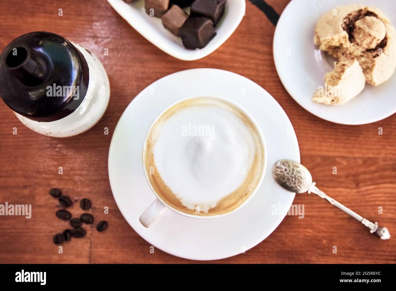 Cup of cappuccino coffee on wooden table with cookie and chocolate. Stock Photo