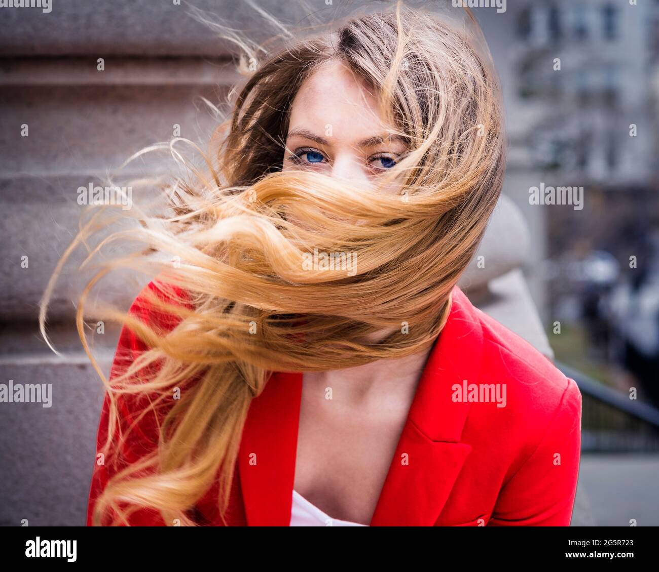 Windy Day. Dressing in red, a young woman with long blonde hair is on a windy day. Stock Photo