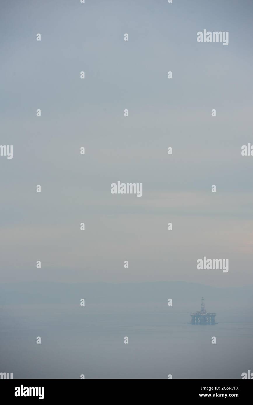 Ghostly oil rig appears to be floating on the North Sea by Upper Largo, Fife, Scotland, with beautiful serene pastel sky and calm water Stock Photo