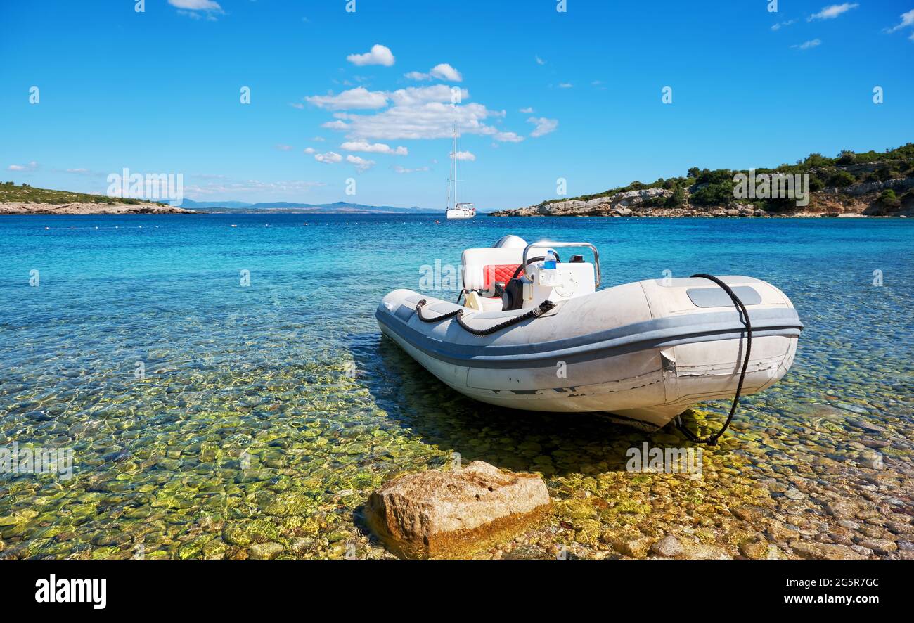 Inflatable rubber motorboat at the shore with beautiful holiday landscape of sea, sun and beach. Stock Photo