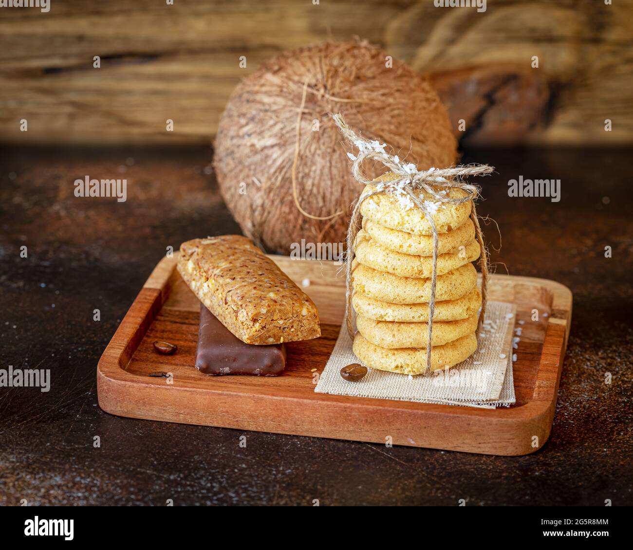 Homemade organic coconut cookies, diet candy bars and whole coconut on a wooden background. Gluten-free, low in carb sweets with coconut Stock Photo