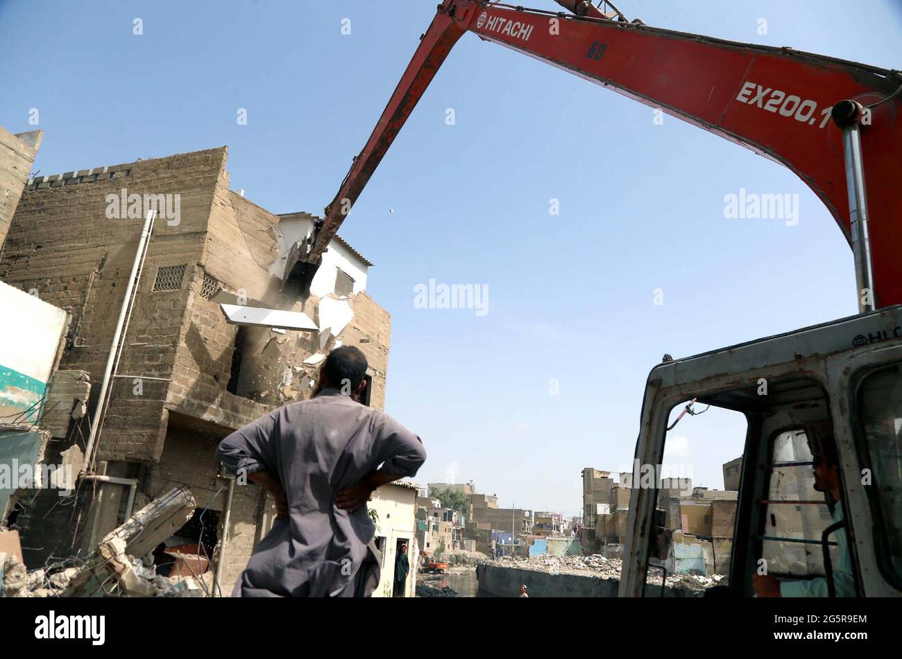 Quetta, Pakistan, June 29, 2021. Heavy machinery and workers busy in demolish encroachments established along with the local Nullah during anti-encroachment campaign under the supervision of Karachi Municipal Corporation (KMC), located on Liaquatabad Chuna Dipo area of Karachi on Tuesday, June 29, 2021. Stock Photo