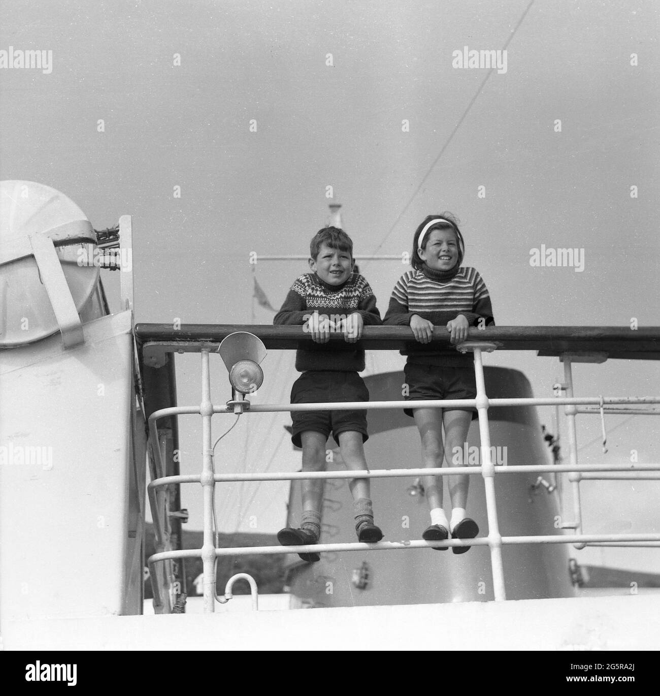 1959, historical, to get the best view to look out, two excited children, a brother and sister standing on the railings on the top of a steam ferry, Scottish Highlands, Scotland, UK. Stock Photo