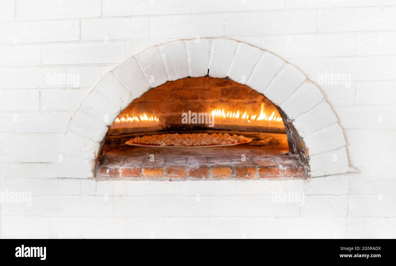 Pizzas or pita bread baking and cooking in open firewood typical brick white oven Stock Photo