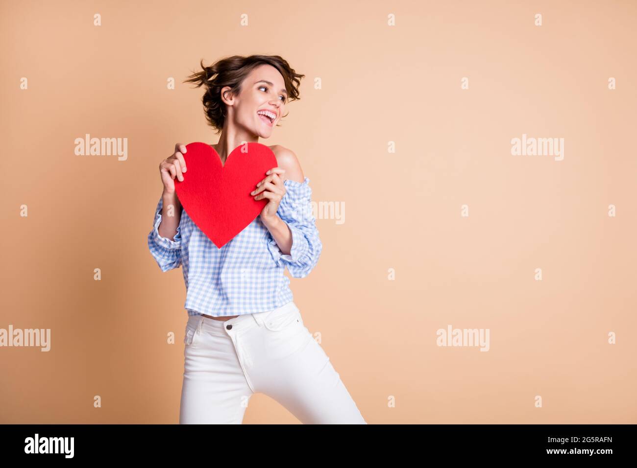 Photo portrait of cute girl holding big red heart card in two hands ...