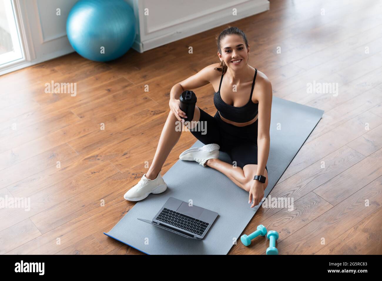 Young woman sitting on yoga mat using laptop Stock Photo - Alamy