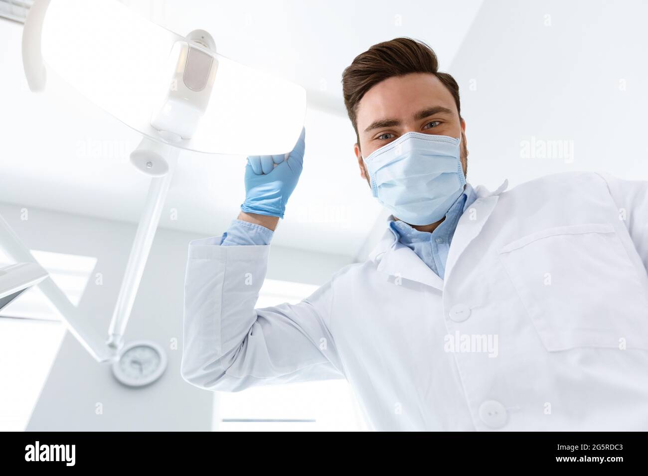 Male dentist turning on lamp, looking at camera Stock Photo