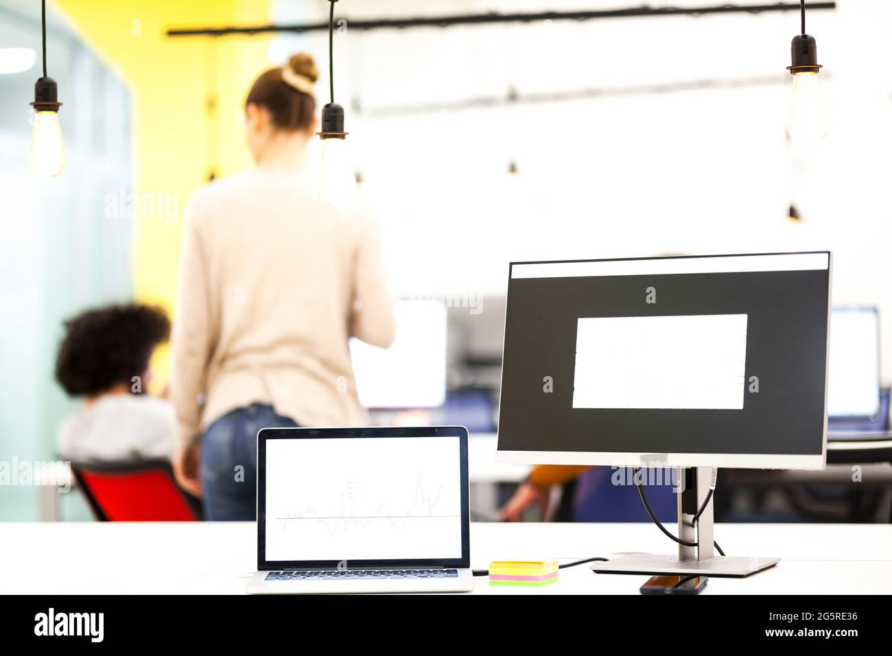 Laptop computer and desktop monitor showing graphs in a modern work space Stock Photo