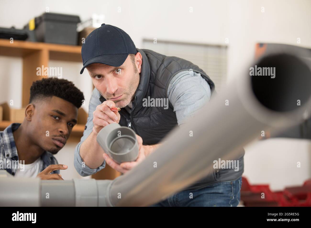 two men assembling plastic waste pipes Stock Photo Alamy
