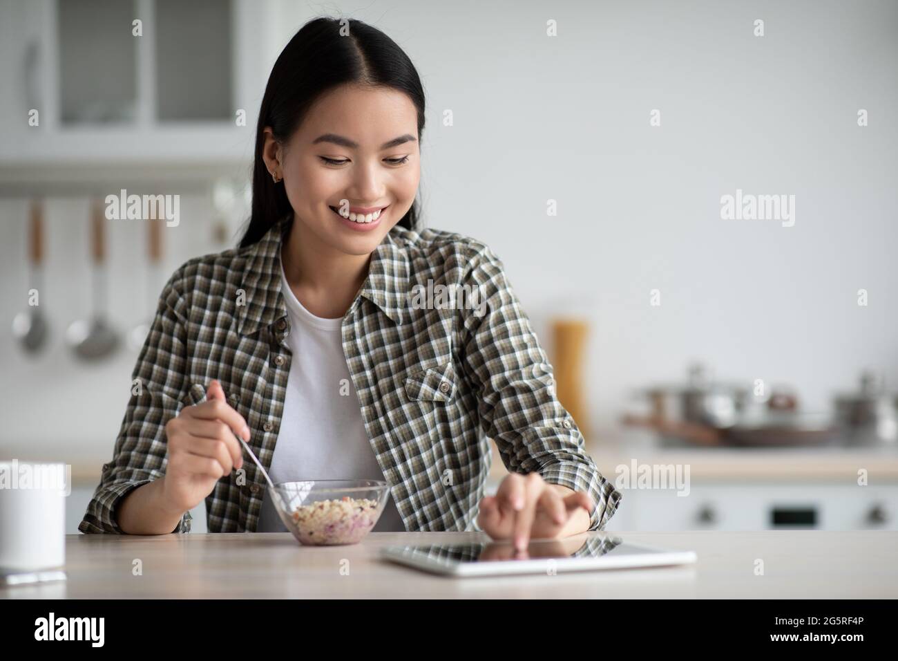 Young asian woman having breakfast and using digital tablet Stock Photo