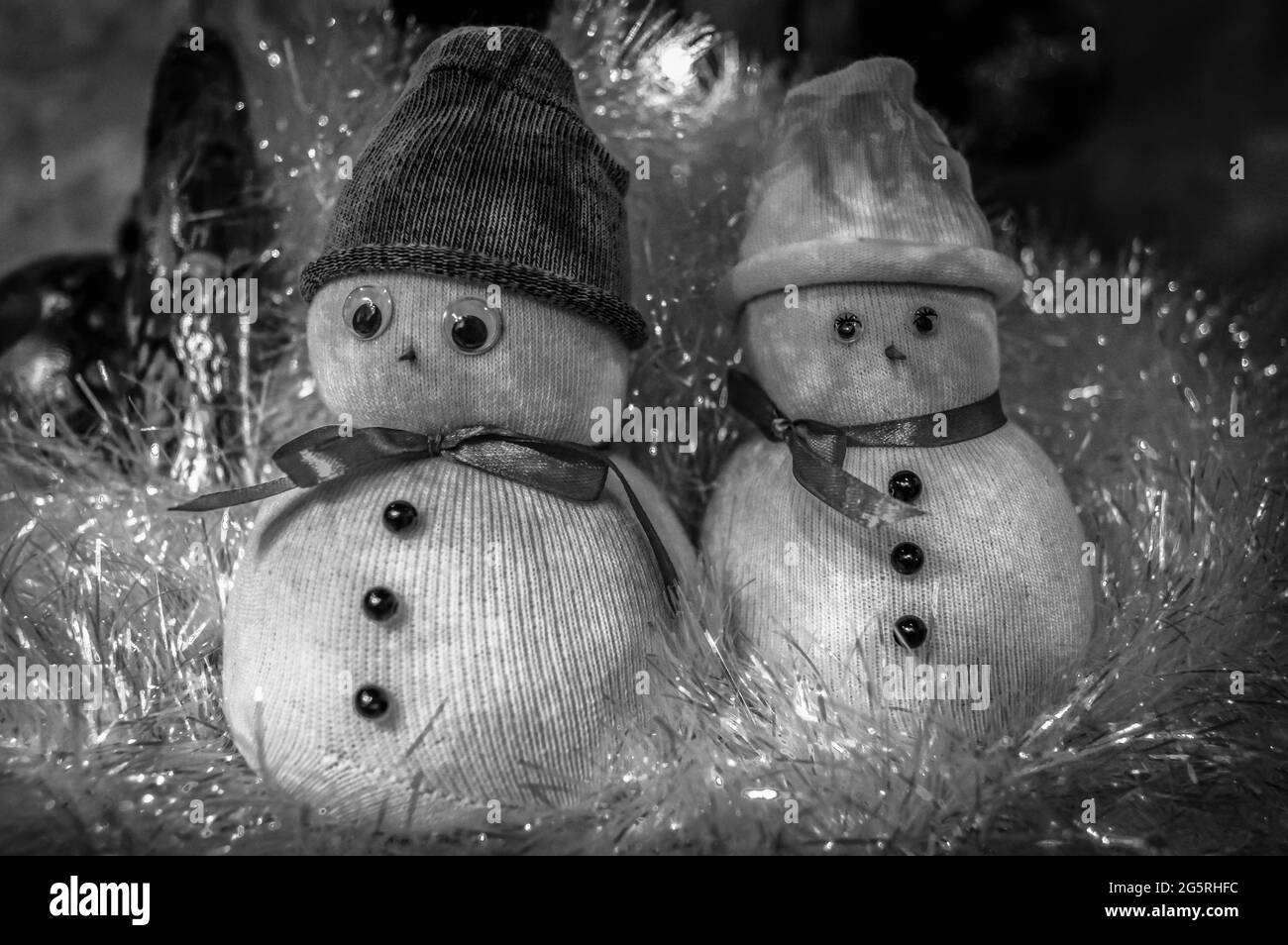 Cute snowmen in caps covered in tinsel at Christmas. Black and white. Stock Photo