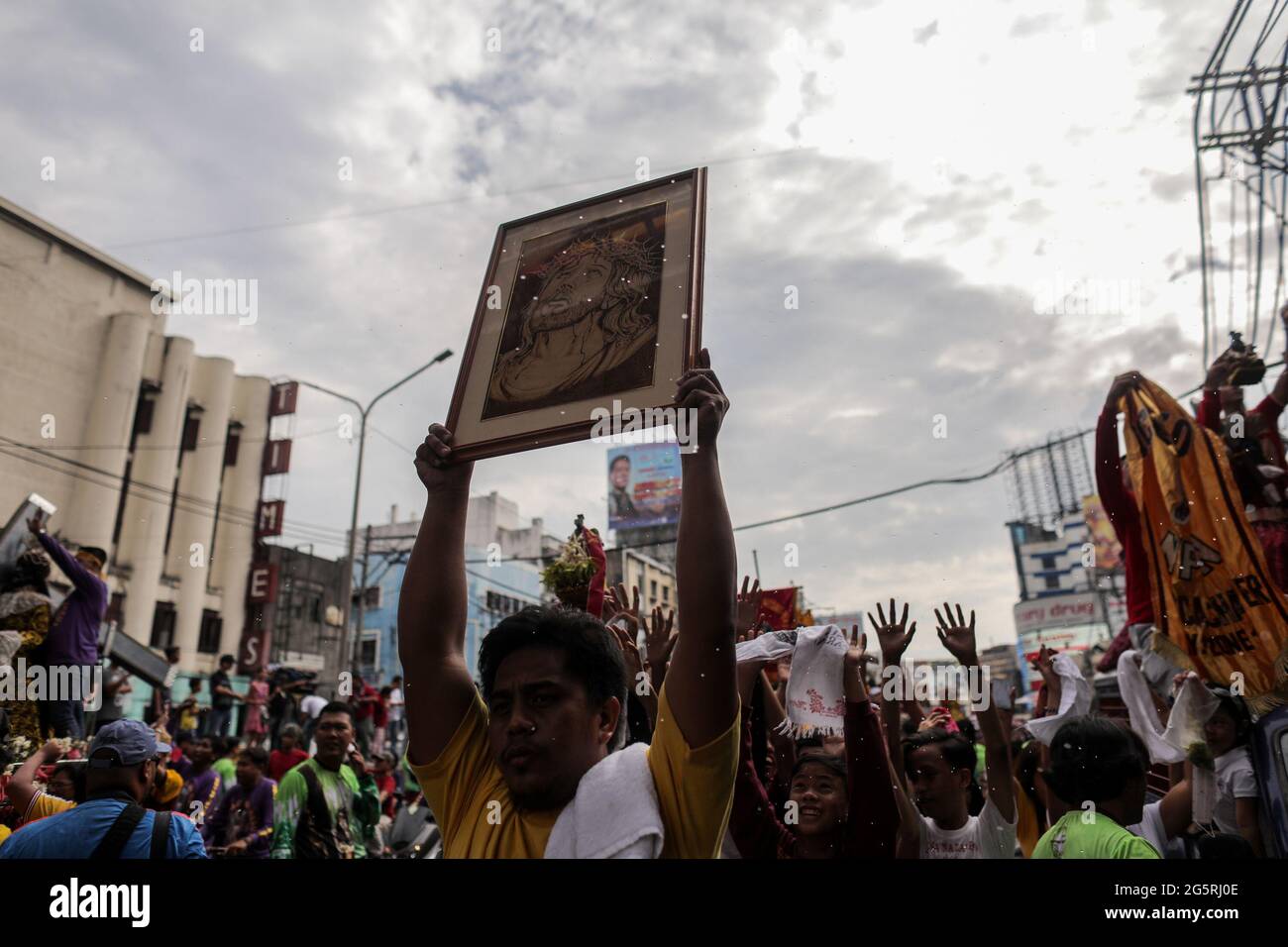 A Filipino Catholic devotee raises a portrait of the Black Nazarene during a blessing of replicas ahead of the Feast of the Black Nazarene in Manila, Philippines. Stock Photo