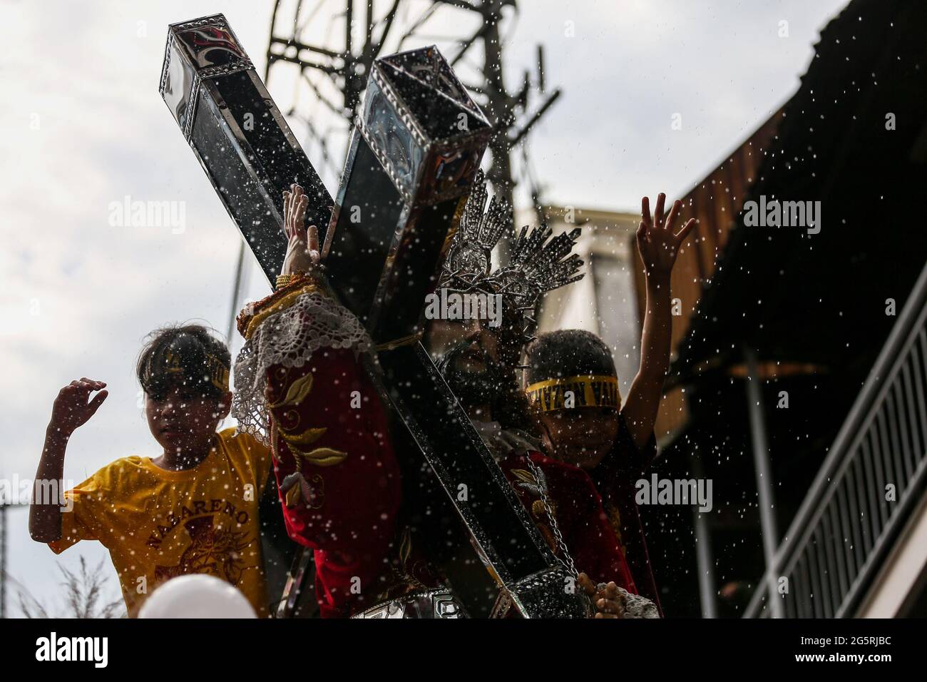 Filipino Catholic devotees raise their hands and towels as priests sprinkle Holy water on Black Nazarene replicas ahead of the Feast of the Black Nazarene in Manila, Philippines. Stock Photo