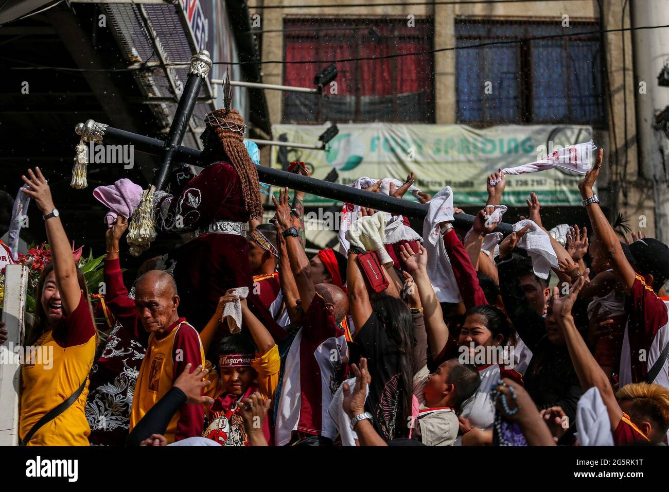 Filipino Catholic devotees raise their hands and towels as priests sprinkle Holy water on Black Nazarene replicas ahead of the Feast of the Black Nazarene in Manila, Philippines. Stock Photo