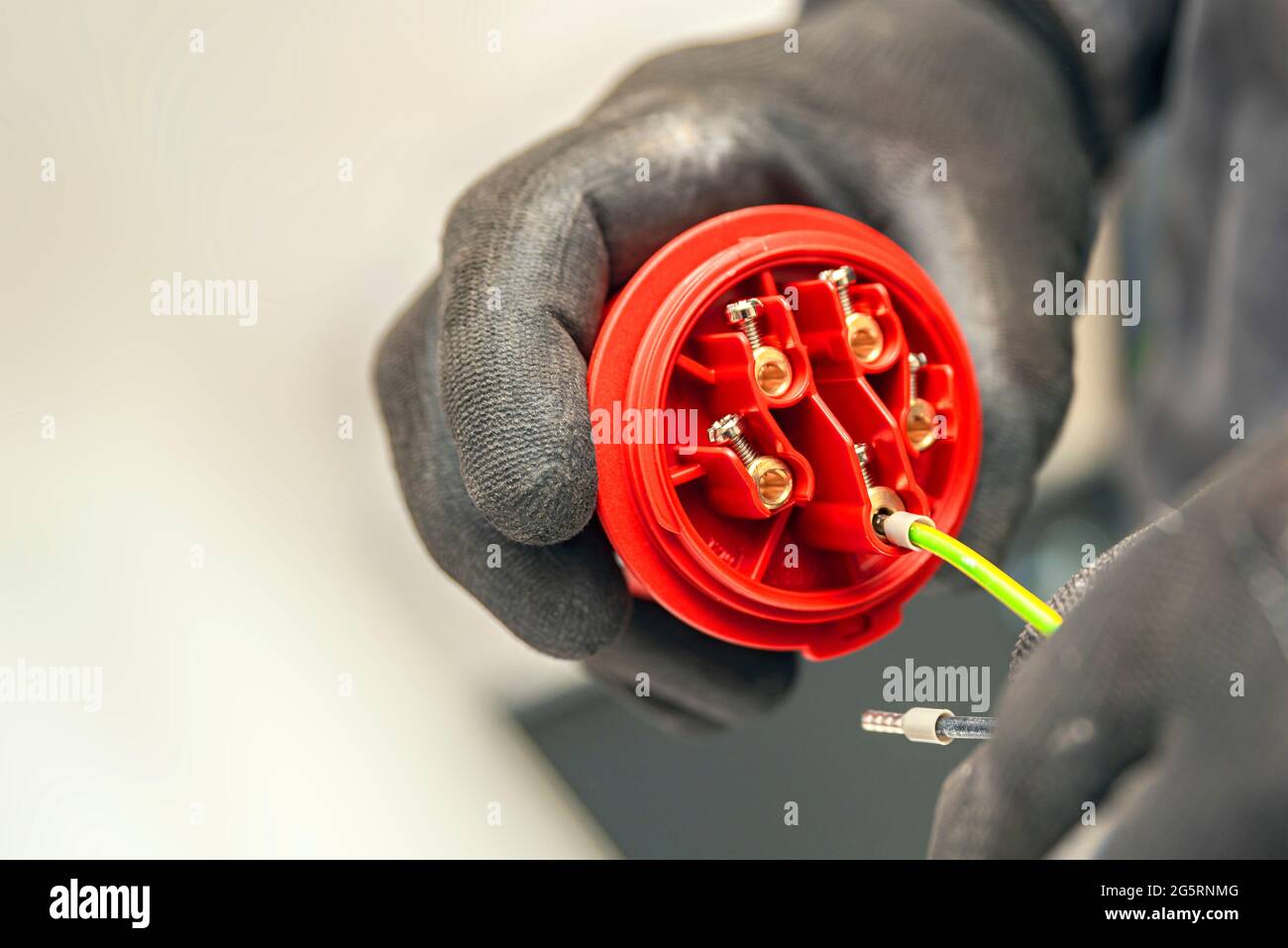 High voltage plug. An electrician wearing protective gloves connects