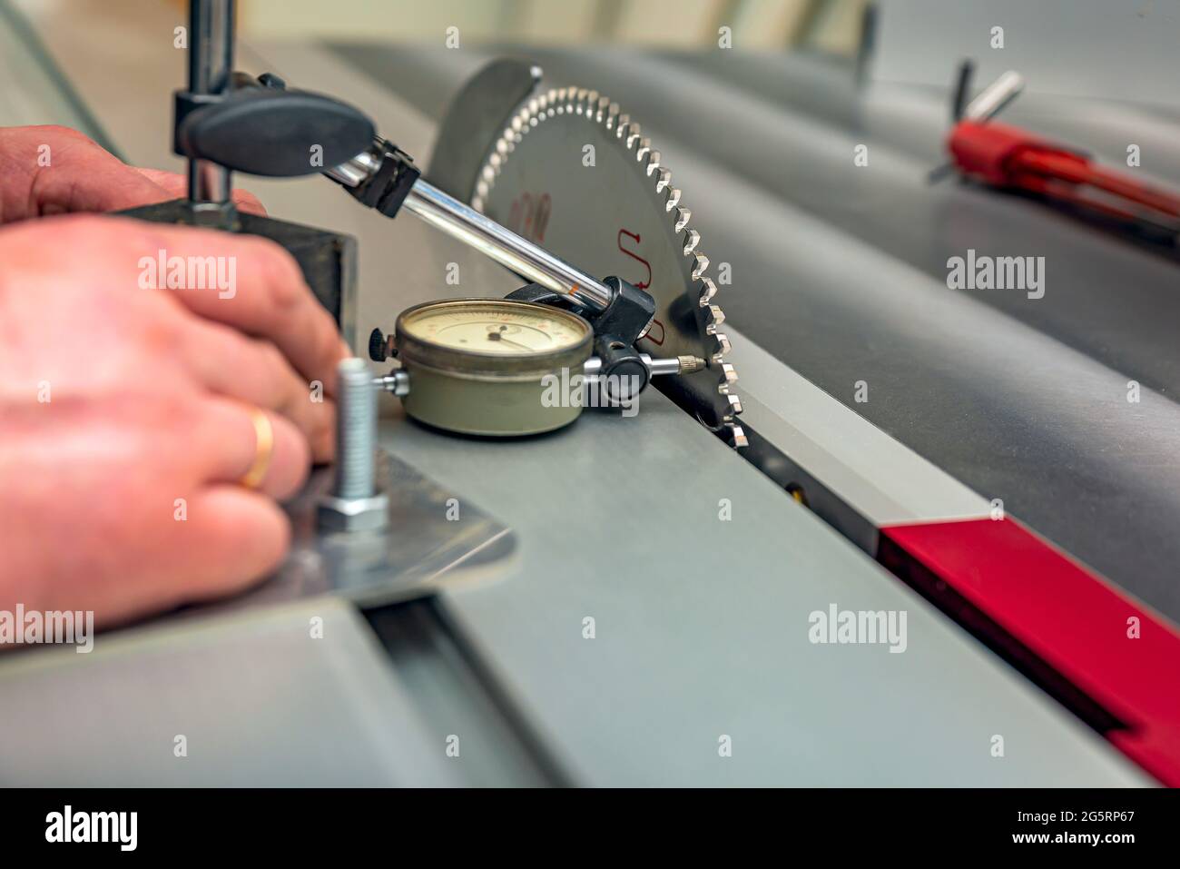 Dial indicator. A worker adjusts a scale indicator to align a saw blade