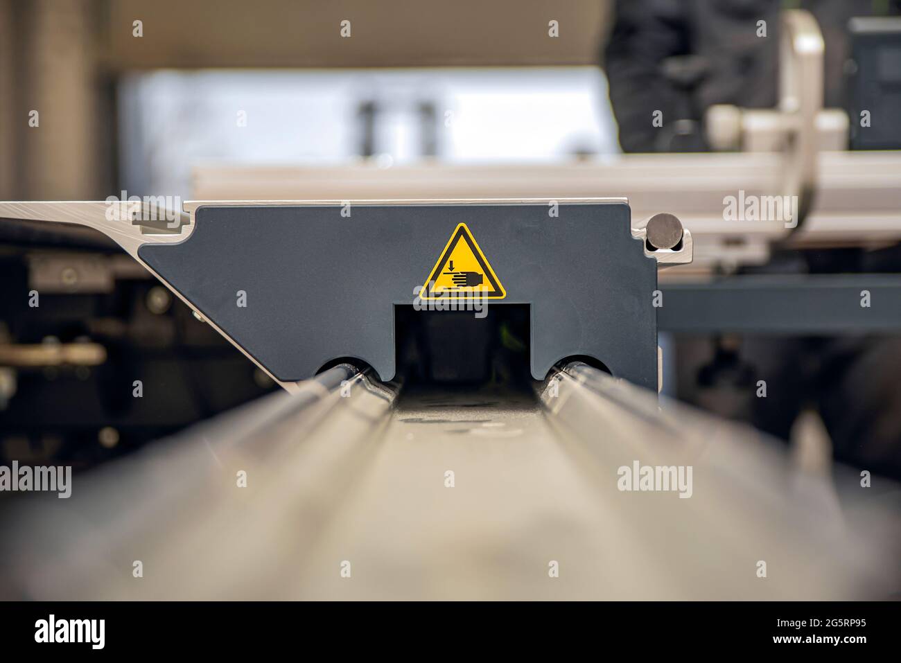 A warning sign on a woodworking machine. Production safety in a carpentry workshop. Hazard sign of moving parts in yellow triangle with hands Stock Photo