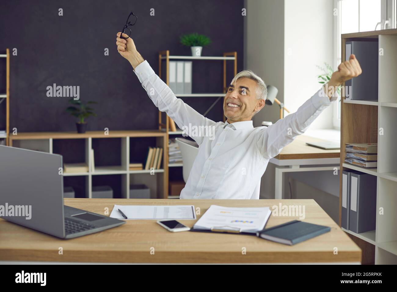 Senior businessman feeling happy and satisfied after finishing work in the office Stock Photo