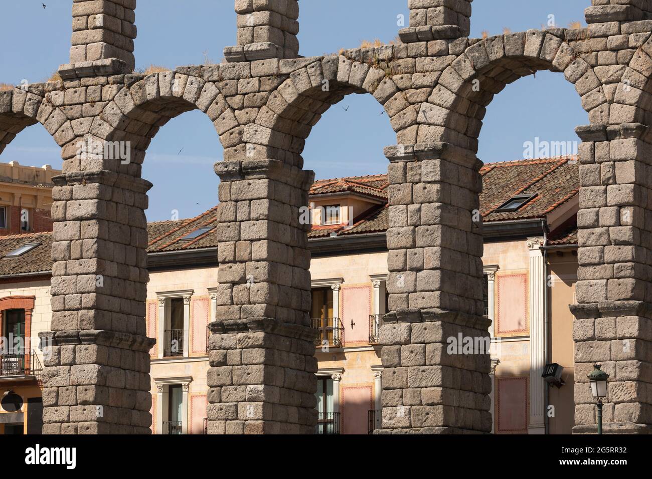 Detail of the granite arches of the Aqueduct of Segovia, crossed by swallows birds, next to the Plaza del Azoguejo Stock Photo
