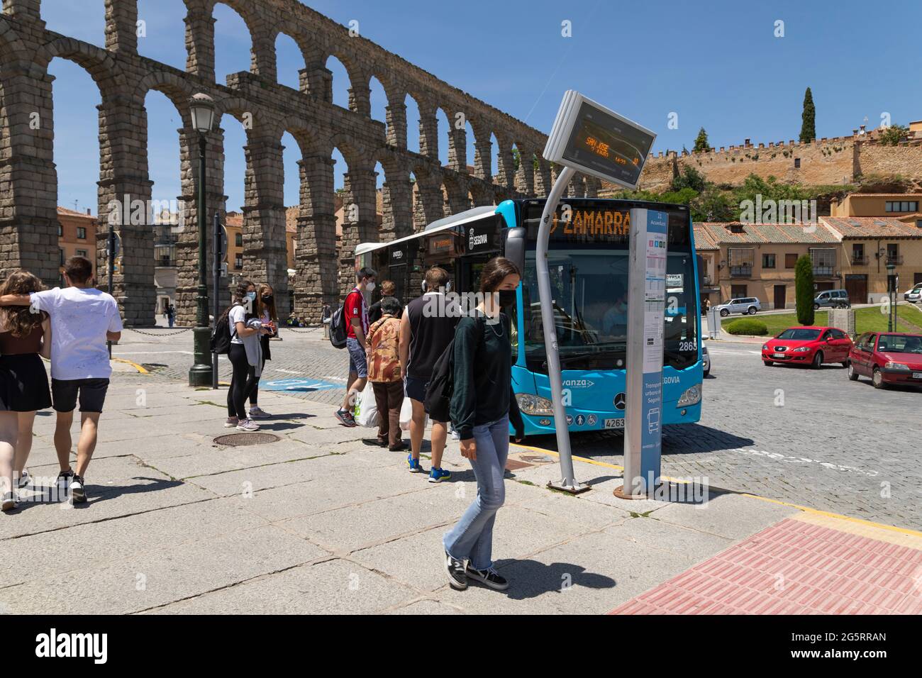 Segovia, Spain - June 2, 2021: Several people wait to get on the bus of line 9, Zamarramala, in front of the Aqueduct of Segovia Stock Photo