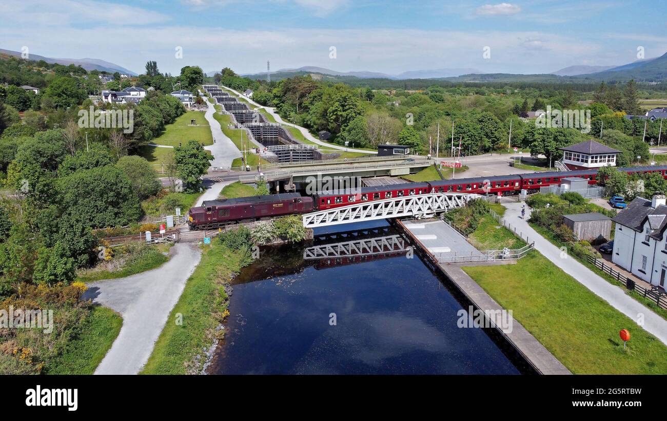 37669 heads over Banavie swing bridge with Neptunes stair case behind on the Caledonian Canal. Stock Photo