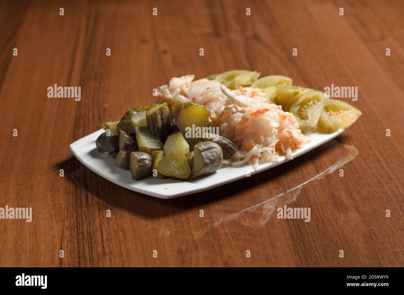 Pickles, sauerkraut, salted green tomatoes in a white plate on the table Stock Photo