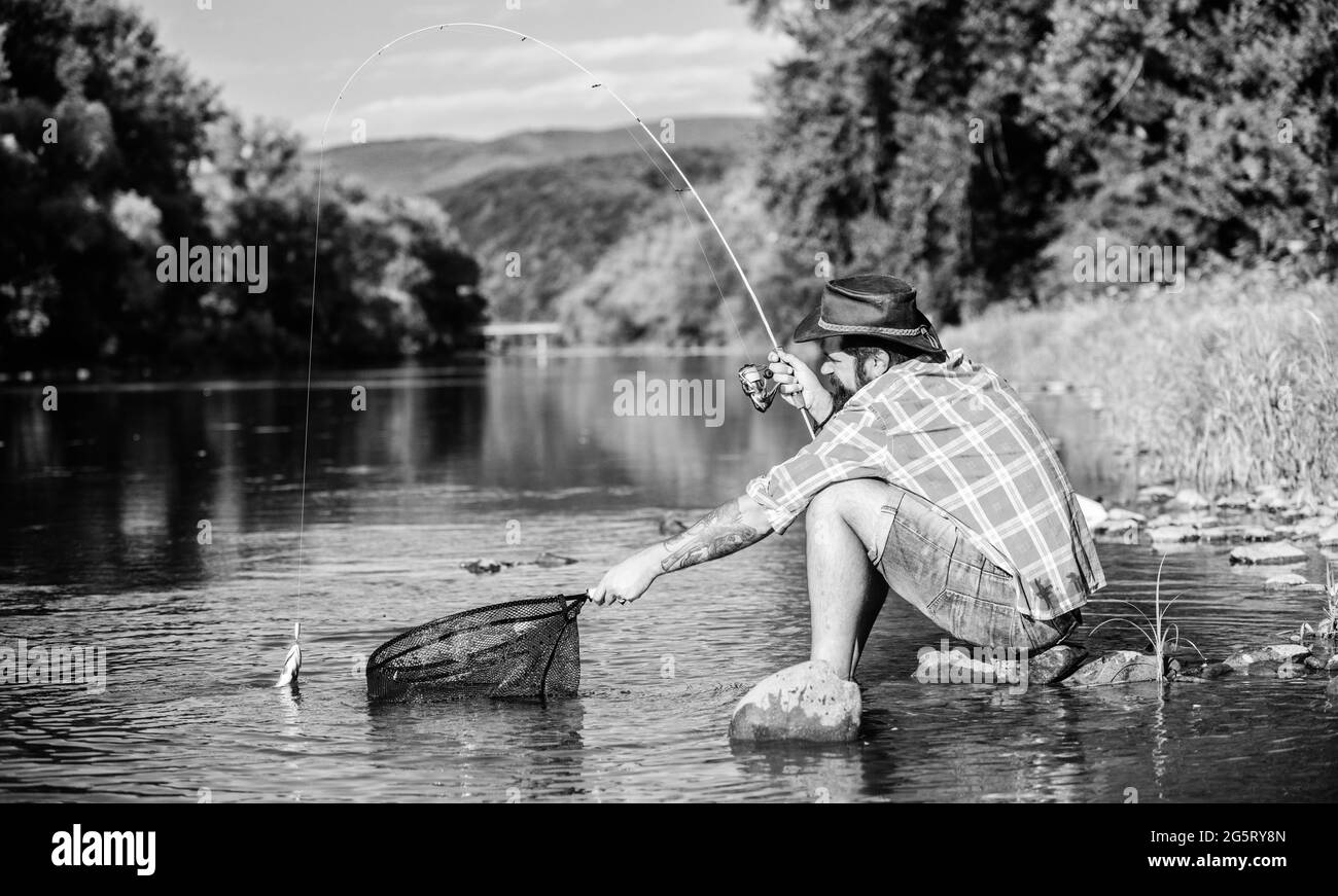 I catch it by myself. bearded man with fish on rod. hipster fishing with spoon-bait. fly fish hobby. Hipster in checkered shirt. successful fisherman Stock Photo