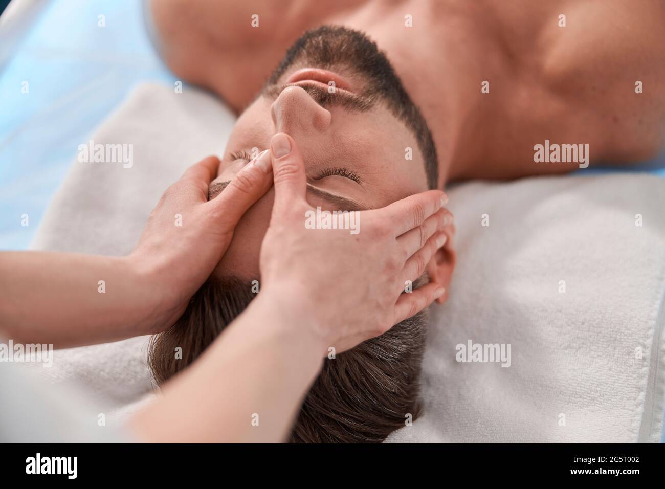 Woman massage therapist works with head of client lying on comfortable couch in spa salon Stock Photo