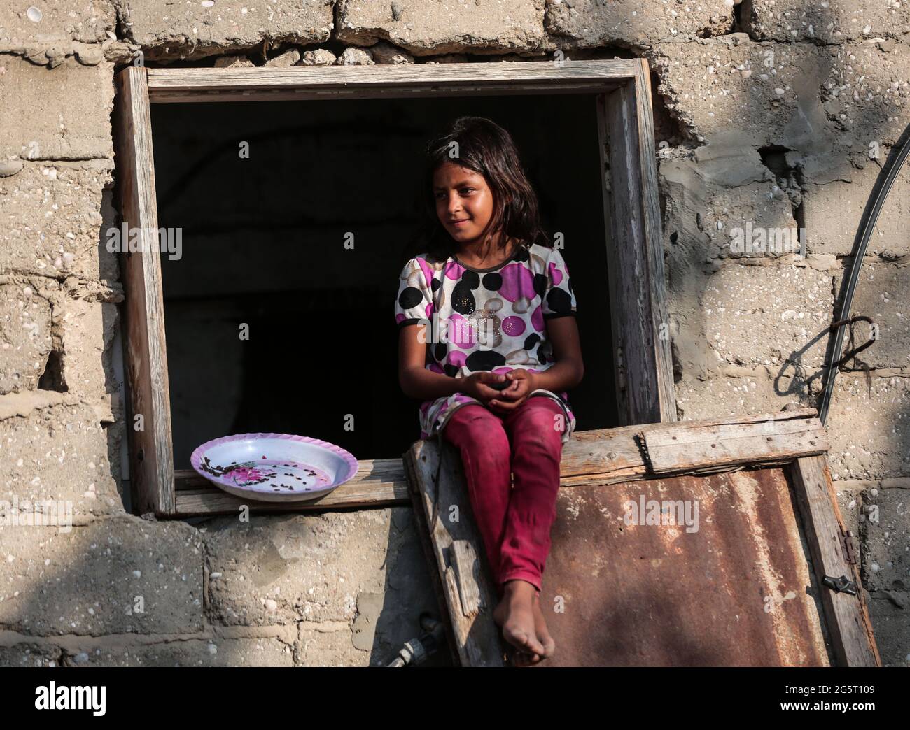 Gaza. 29th June, 2021. A Palestinian girl sits at the window of a house ...