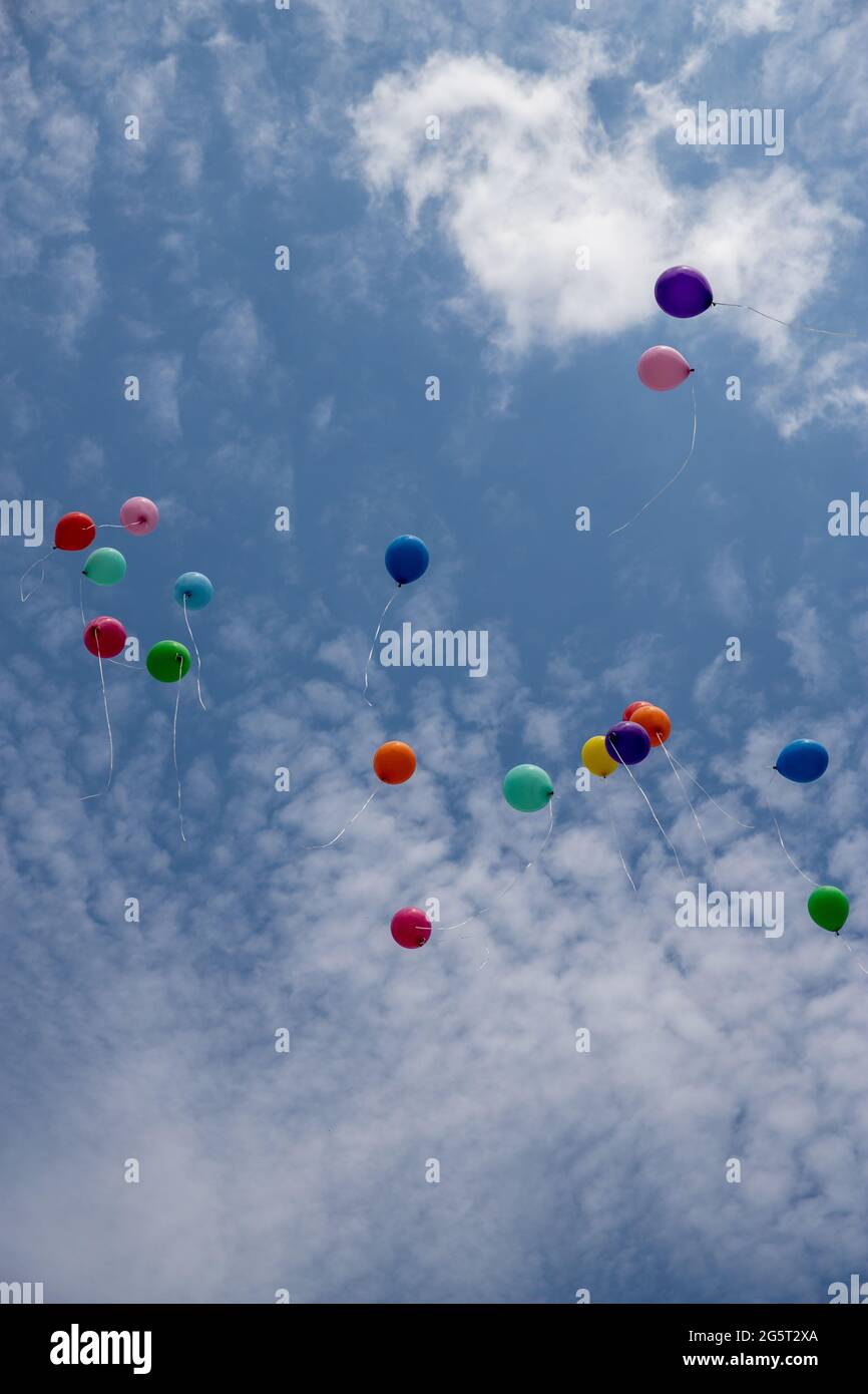 colored and multi-colored gel balloons are flying in a group of bright blue skies Stock Photo