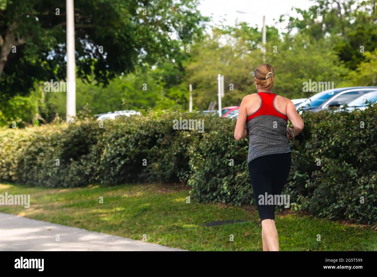 Gainesville, USA - April 27, 2018: University of Florida UF campus grounds with woman female student running jogging exercising in morning on sidewalk Stock Photo