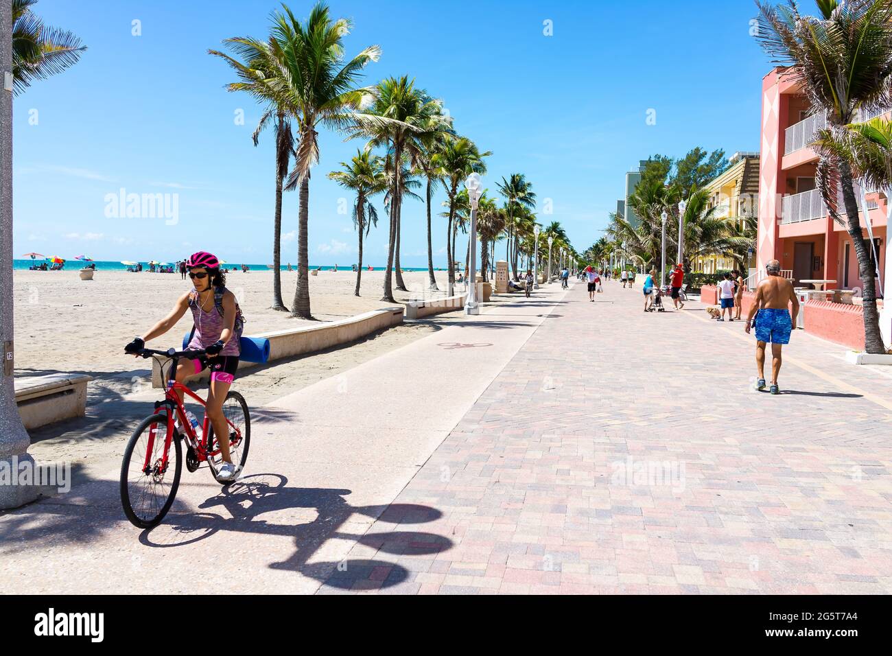 Hollywood, USA - May 6, 2018: Beach broadwalk path in Florida at sunny day and candid people riding bikes on promenade Stock Photo