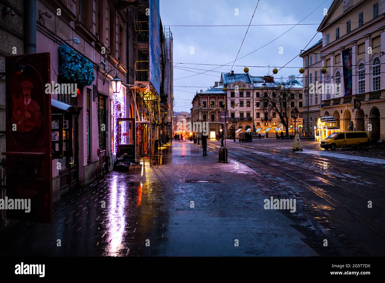 Lviv, Ukraine - December 28, 2019: Old town market square street in Lvov with winter snow at dark evening night with empty road and reflection Stock Photo