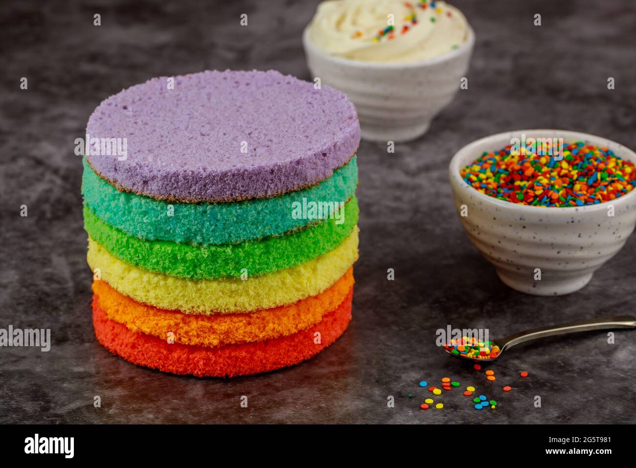Cake assembly. layer cake with white icing and sprinkles. Stock Photo