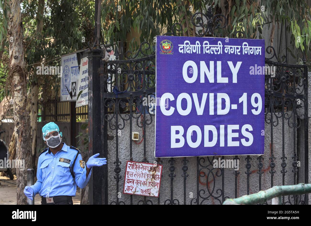 New Delhi, India. 15th June, 2020. A masked security guard stands outside a cremation grounds next to a sign that grimly states 'ONLY COVID-19 BODIES'. Credit: Vijay Pandey/ZUMA Wire/Alamy Live News Stock Photo