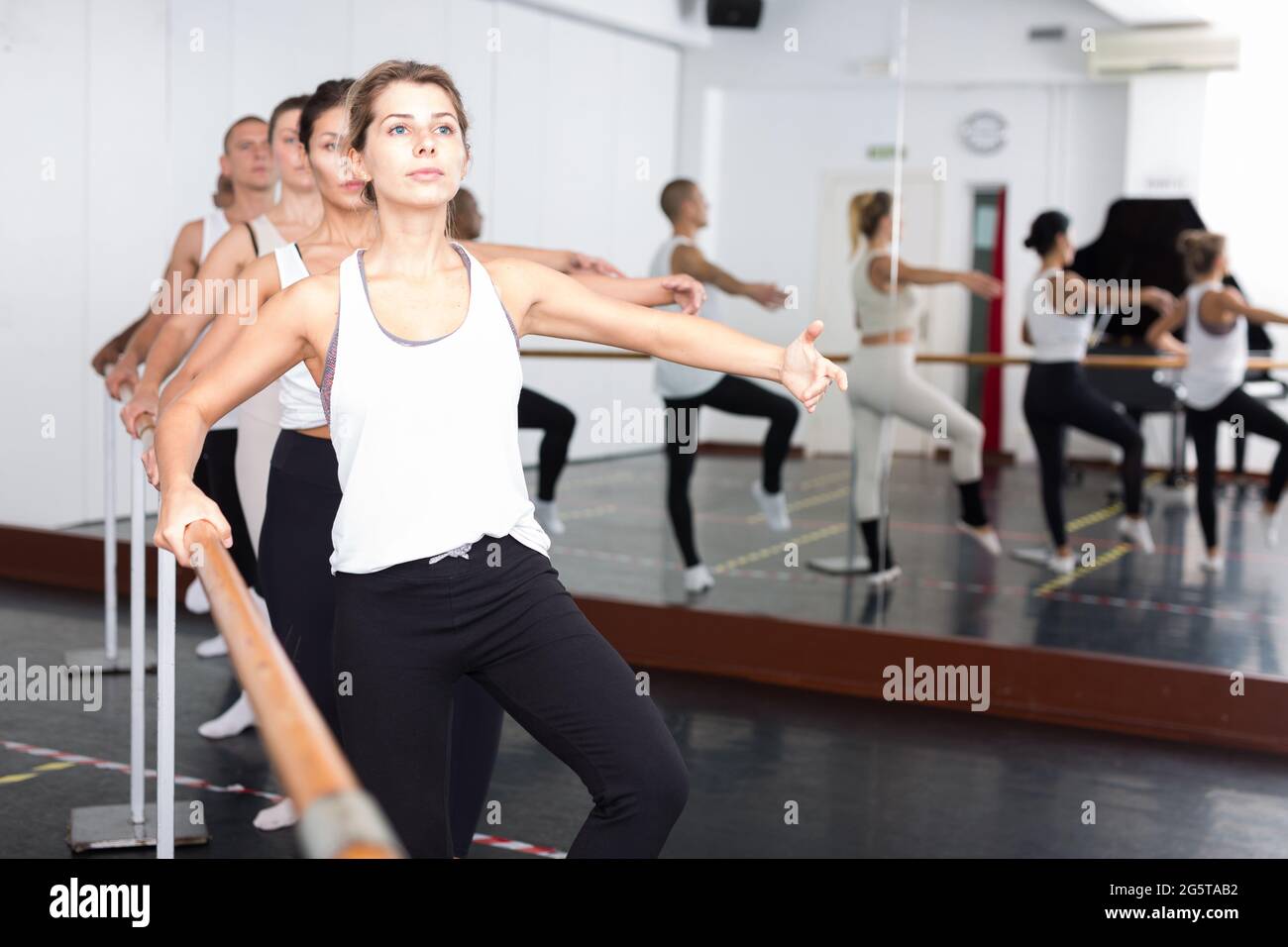 people doing exercises on stretching ballet barre Stock Photo