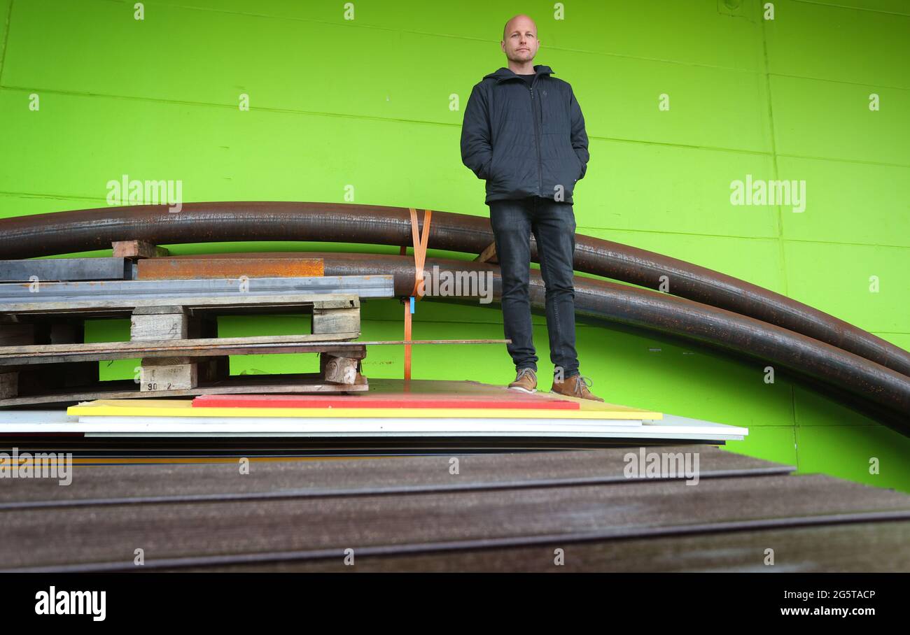 Durach, Germany. 06th May, 2021. Dirk Scheumann, managing director of the pumptrack manufacturer 'Schneestern', stands in front of his company's production hall among building materials. In more and more German cities, asphalt facilities like this are springing up, and it's not just cyclists who are having fun on them. Credit: Karl-Josef Hildenbrand/dpa/Alamy Live News Stock Photo