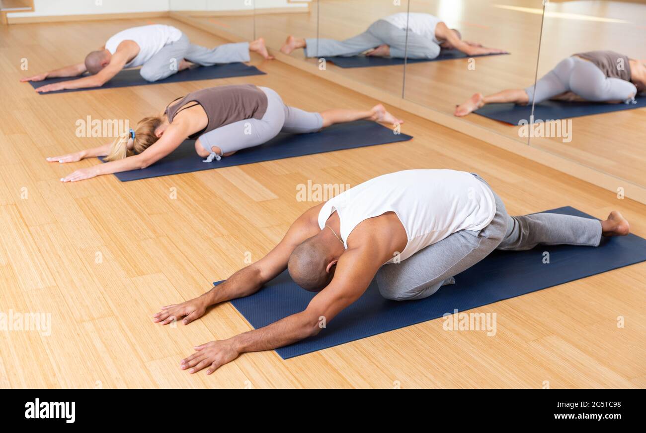 Woman and men stretching during group yoga training Stock Photo