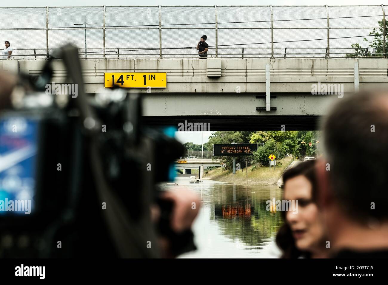 Detroit, US, 28/06/2021, A Detroit resident watches from an overpass as Governor Gretchen Whitmer holds a press conference on a still flooded portion of I-94 in Detroit. After a weekend of heavy storms beginning on Friday night and lasting through the weekend rainwater flooded parts of I-94 in Detroit, Michigan forcing some motorists to abandon their vehicles and seek shelter from the heavy rains. Flood waters remained in areas along I-94 between Dearborn and Downtown Detroit several days later as Michigan Governor Gretchen Whitmer held a press conference on the still inundated I-94. Stock Photo