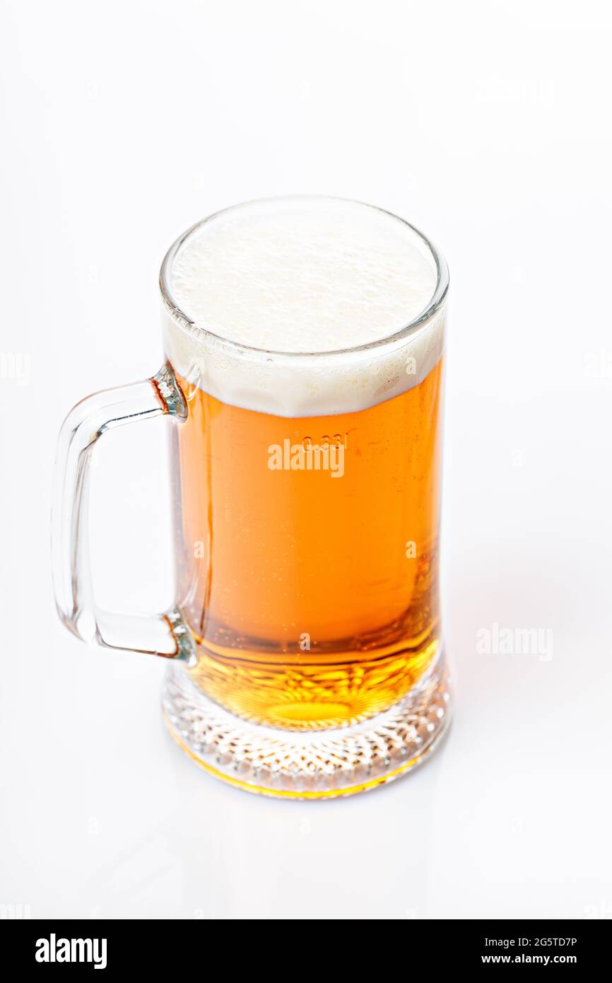 Mug of cold light beer on a white background. Beer foam and bubbles. Vertical shot. Traditional light alcoholic drink shot. Close-up Stock Photo