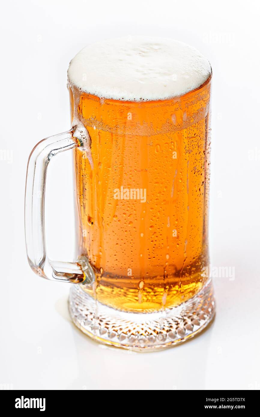 Close-up mug of cold light beer on a white background. Beer foam and bubbles. Vertical shot. Traditional light alcoholic drink shot. Stock Photo