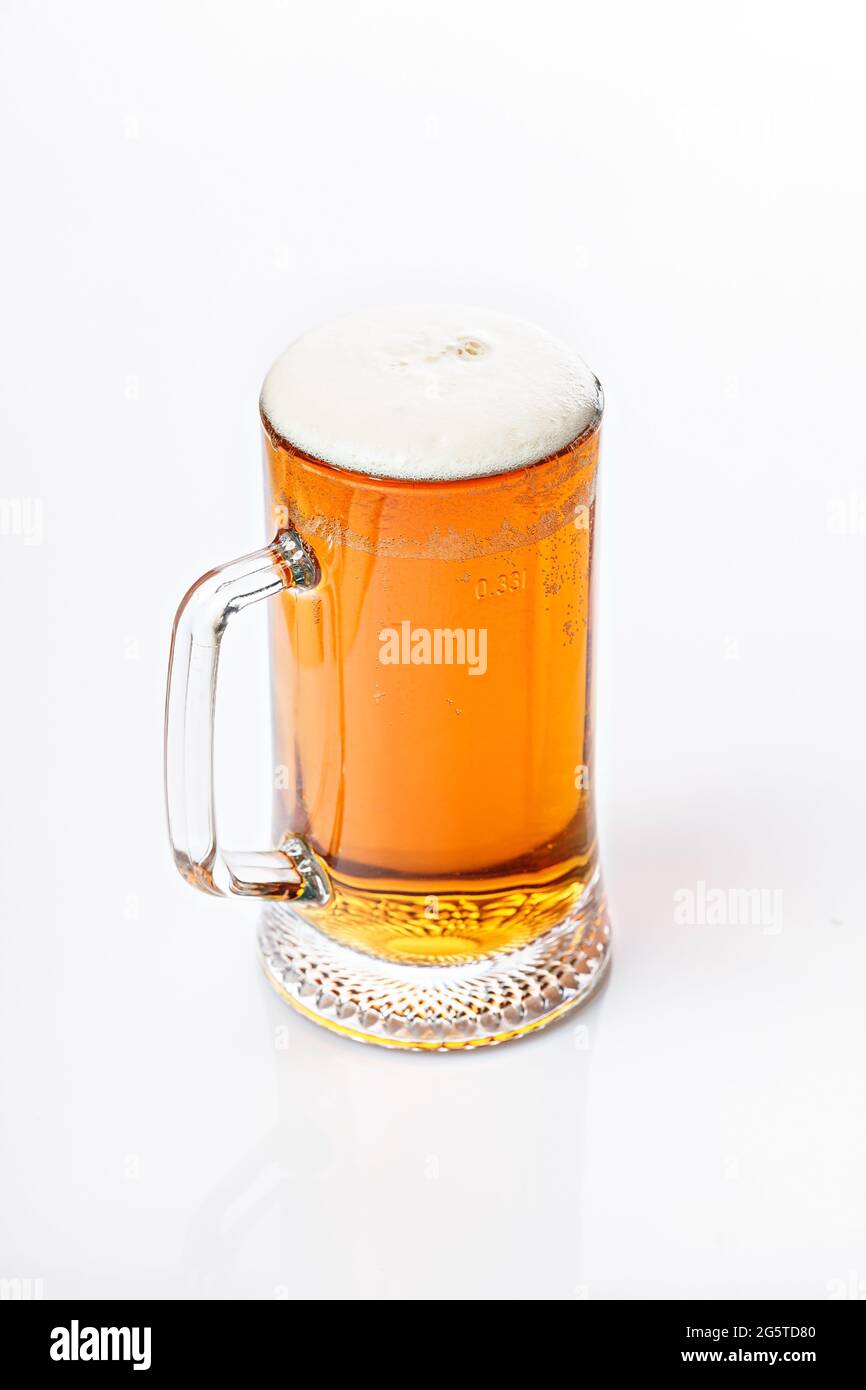 Mug of cold light beer on a white background. Beer foam and bubbles. Vertical shot. Traditional light alcoholic drink shot. Close-up. Copy space Stock Photo