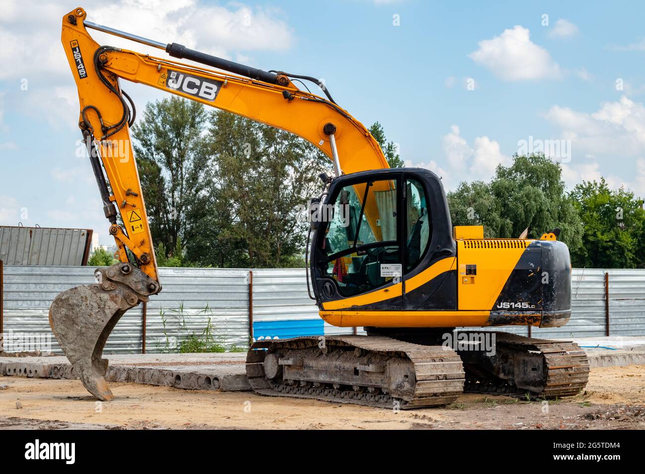 The dirty yellow JCB crawler excavator with bucket at the construction site. Illustrative editorial Stock Photo