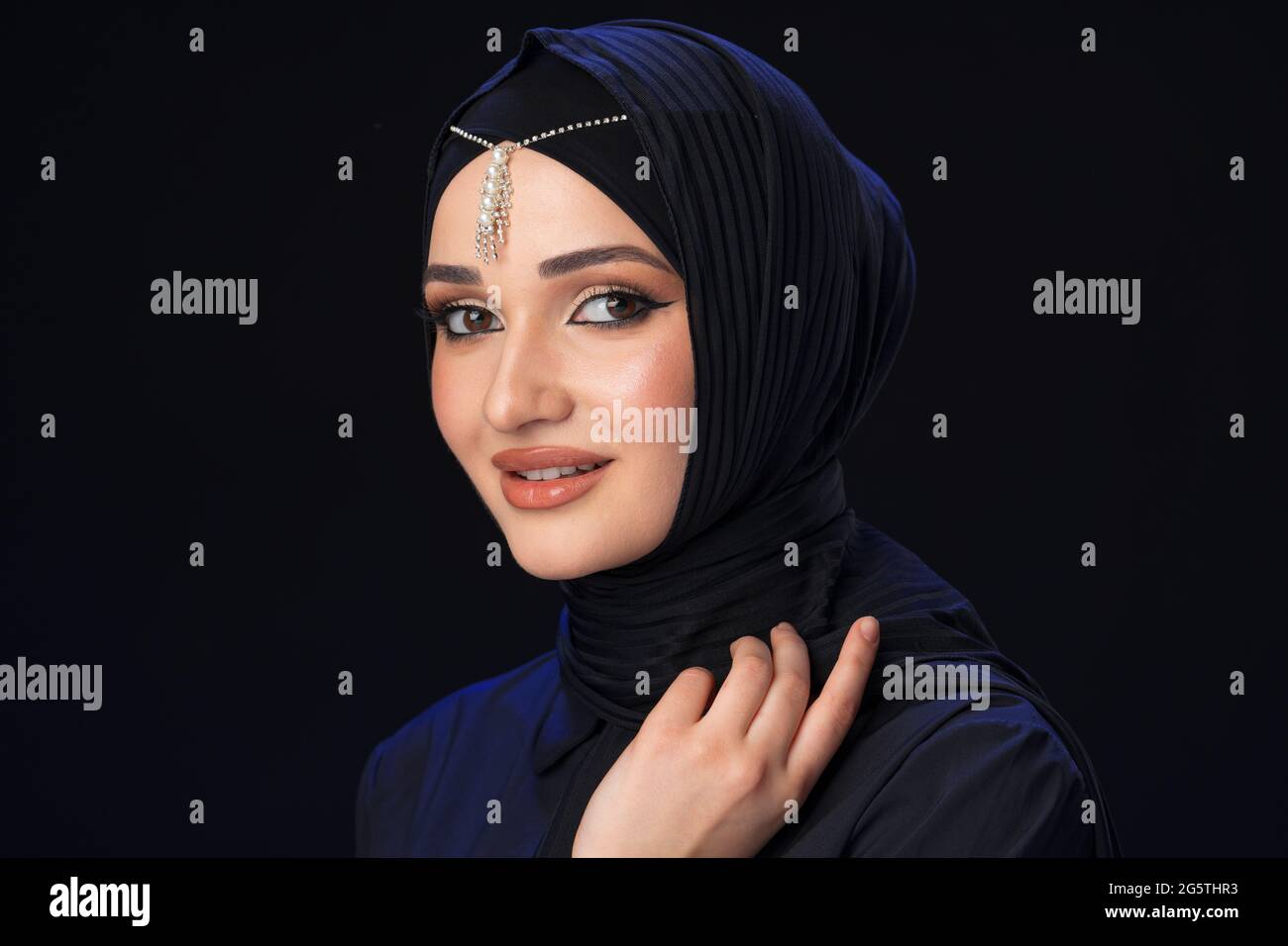 Portrait of a young muslim woman in hijab on black background Stock