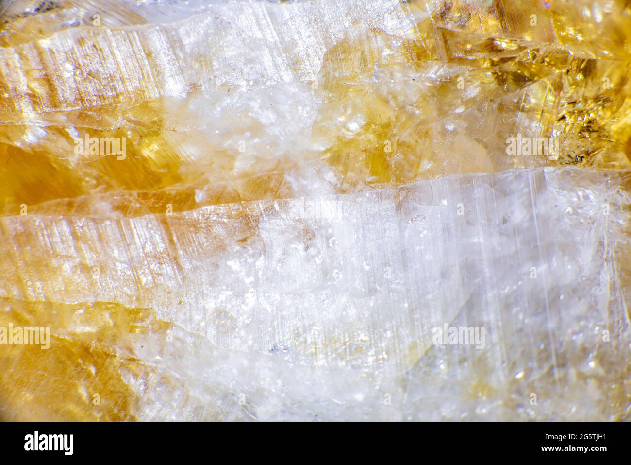 macro shooting of natural rock specimen. Raw crystal of Citrine yellow quartz gemstone from Brazil. Shimmering gold background. High quality photo Stock Photo